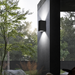 Axis black up and down wall light with cool white illumination on a porch column. Style illustration.